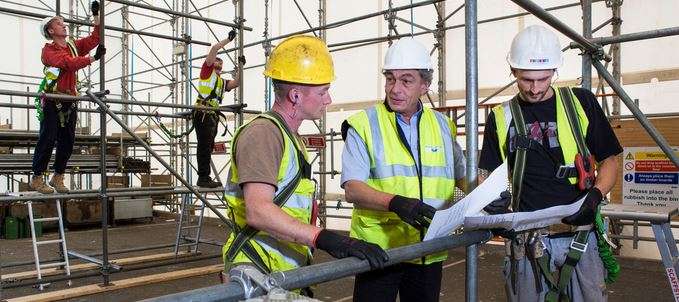 men erecting scaffold and reading plans