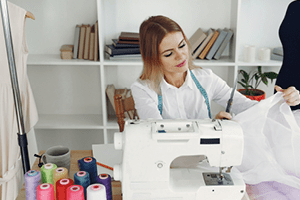 - a young woman making an article of clothing at a sewing station