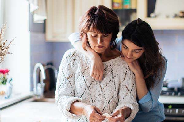 a mother and daughter embracing in a home kitchen