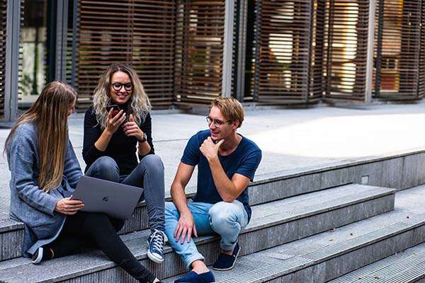 three young adults sat together on concrete stairs